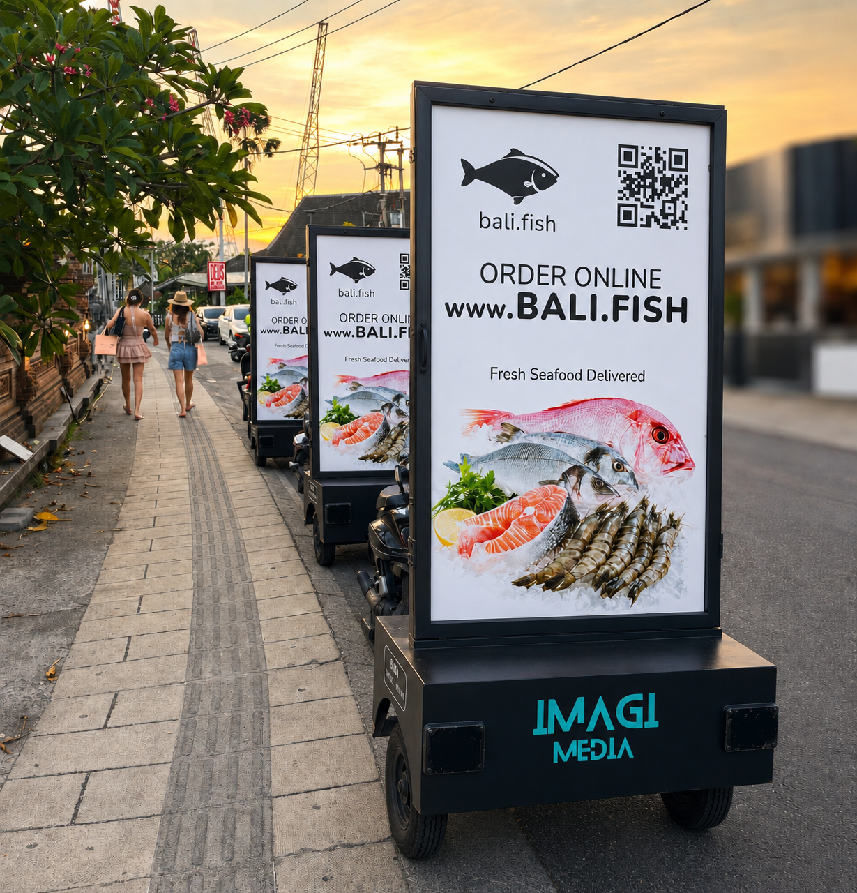 Imagi Media mobile billboards on a Bali sidewalk at sunset advertising bali.fish seafood delivery.
